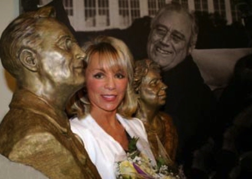 A woman standing next to two statues of people.