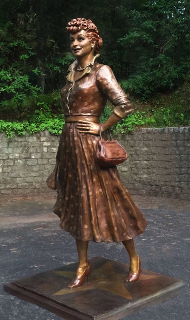 A statue of a woman in a dress and purse.