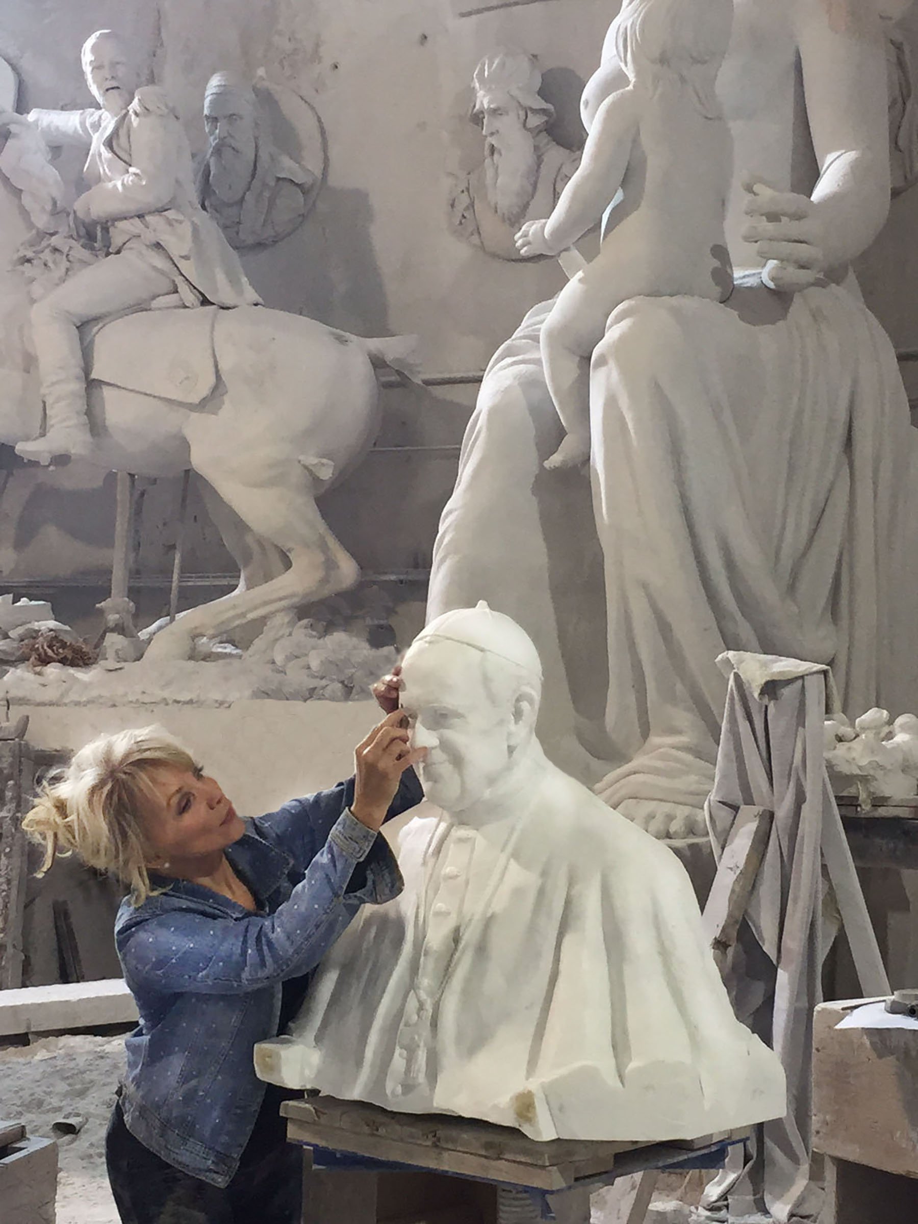 A woman is painting the face of a statue.