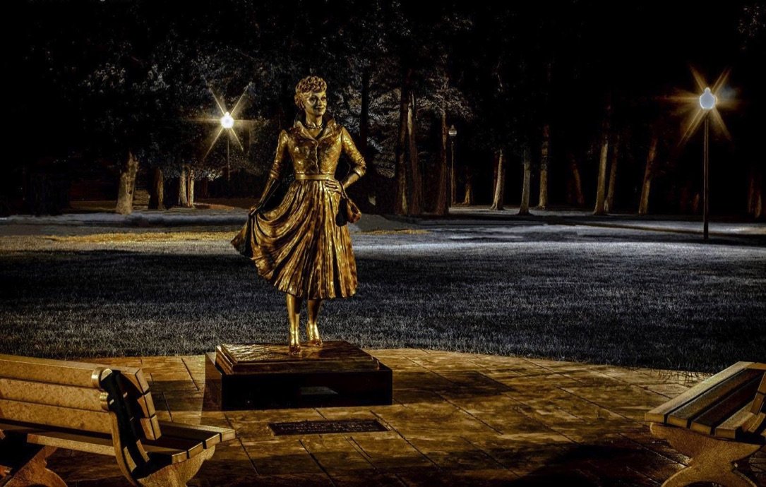 A statue of a woman in gold dress on the ground.