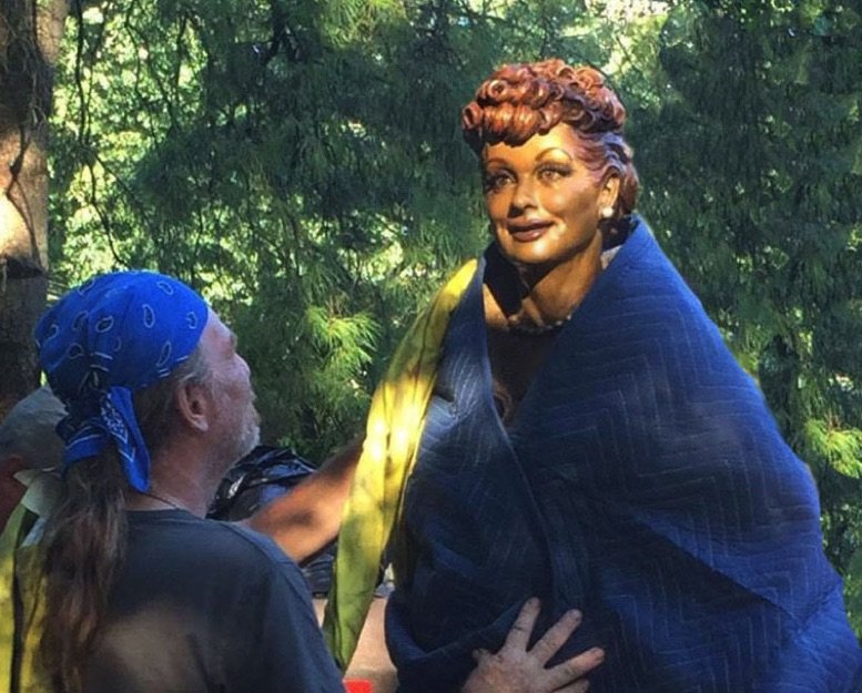 A man is standing next to a statue of a woman.