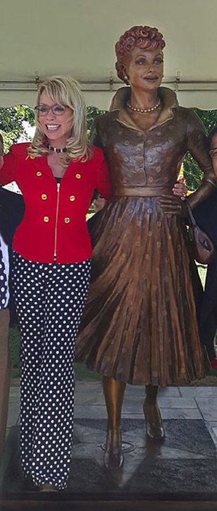 A woman in red jacket standing next to statue.
