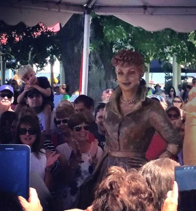 A woman in a costume walks among the crowd.